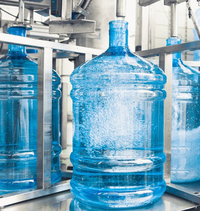 Large blue water jugs on industrial filling line for bottled water delivery service