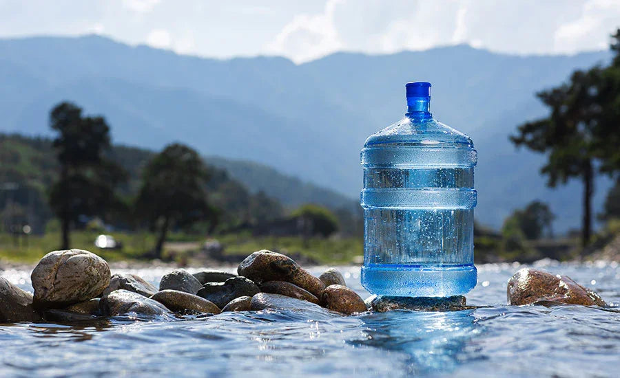 Large water jug in stream with mountain backdrop, pure drinking water delivery